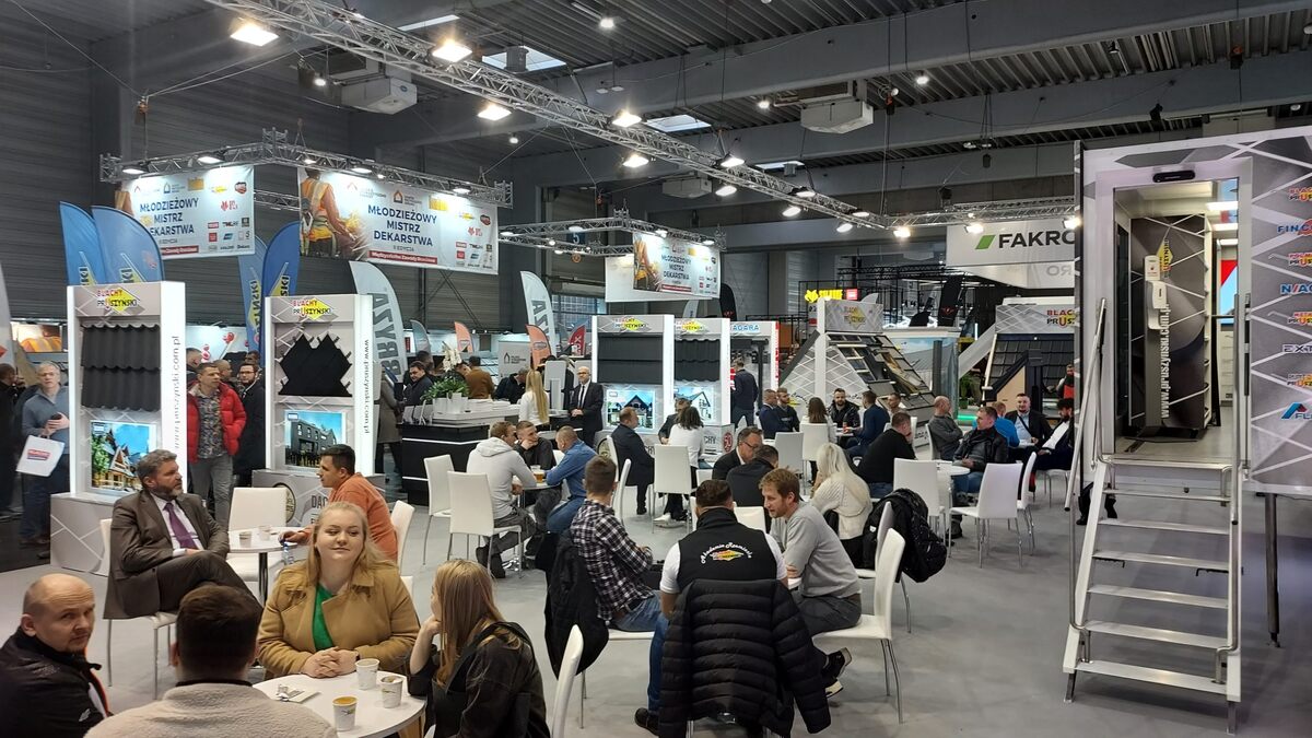 architectural design expo in Poland in a hall with white screen, podium, black lighting fixtures