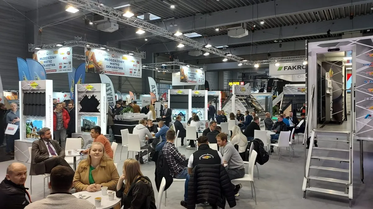 architectural design expo in Poland in a hall with white screen, podium, black lighting fixtures